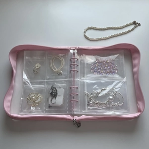 Macro detail of pink loose-leaf jewelry storage book with transparent PVC zipper bags