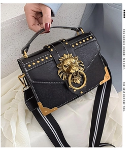 Detail of retro black leather bag with gold lion head buckle and studded accents