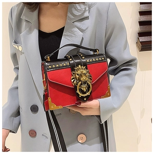 Detail of red PU crossbody bag with golden lion head emblem and striped wide strap