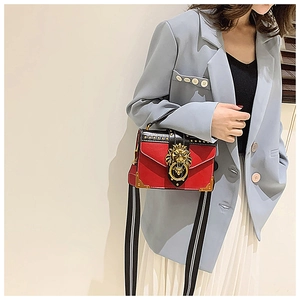 Detail of red and black handbag with golden lion head emblem and striped shoulder strap