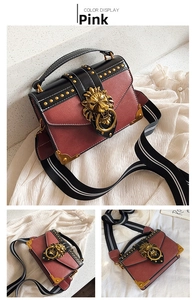 Detail of vintage crossbody bag with gold lion head ornament and rivet accents