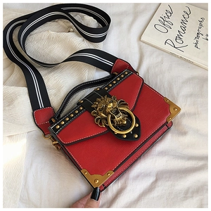Close-up of red PU crossbody bag featuring golden lion head lock and striped strap