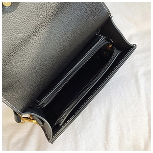 Detail view of black litchi pattern leather bag interior with gold zipper and compartments