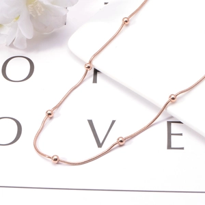 Detailed macro view of rose gold snake chain necklace with small metal beads on LOVE card