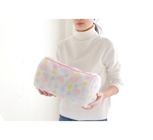 Detailed view of cylindrical mesh laundry bag with cute cartoon prints and pink zipper