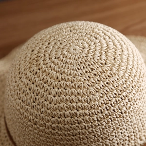 Macro detail of beige woven straw sun hat showcasing fine craftsmanship and texture