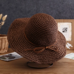 Detail of a dark brown woven straw sun hat with a fine texture and decorative bow tie