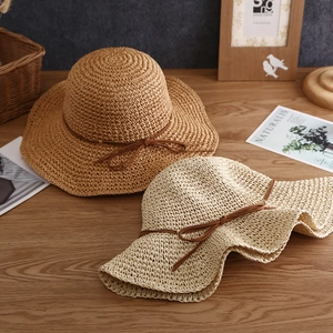 Detail of wide-brimmed paper straw sun hats with elegant bow decoration on wooden surface