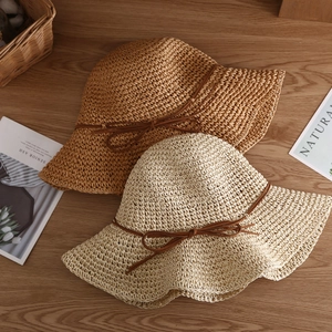 Straw sun hat with wide brim and bow decoration on a rustic wooden table background