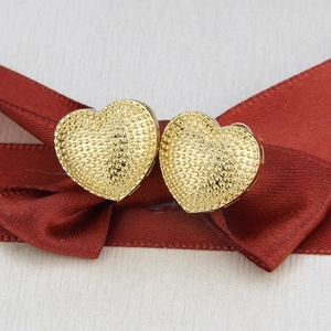 Macro view of 18k gold plated heart earrings with granulation texture on red ribbon