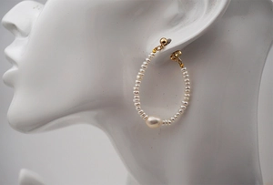 Detail of freshwater pearl earrings with gold U-shaped hardware on a model bust