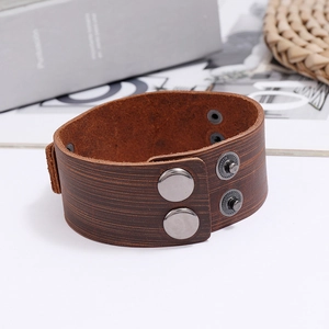 Detail of dark brown leather cuff with metallic silver snap buttons and textured finish
