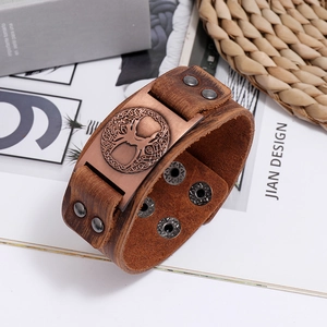 Detailed view of the tree of life bronze metal plate on a wide brown leather bracelet