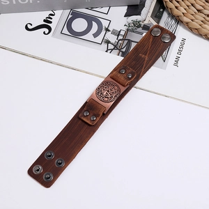Brown leather wide bracelet with bronze Tree of Life charm on a vintage magazine