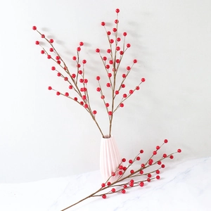 Artificial red berry branches for Christmas home decor in a minimalist white vase