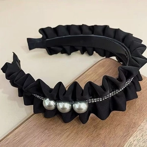Pleated black headband with large pearls and crystal rhinestones on a wooden base