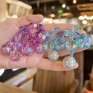 Handheld view of four colorful faceted cherry hair ties in purple and teal blue colors