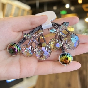 Close-up of translucent cherry hair ties with iridescent finish on a handmade card