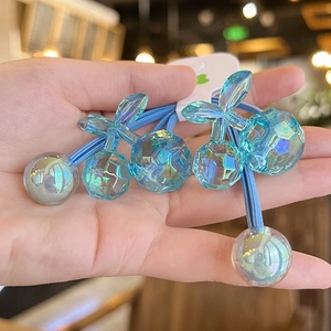 Close-up of blue cherry-shaped acrylic hair ties with faceted charms and elastic bands