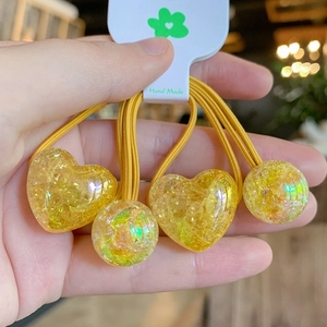Close-up of yellow hair ties with heart and sphere resin charms containing glitter
