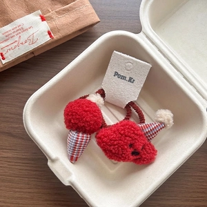 Close-up of red lamb wool hair ties with cute strawberry and pom-pom details in a gift box