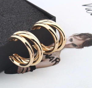 Detail view of triple-layered golden C-shaped hoop earrings with polished mirror finish