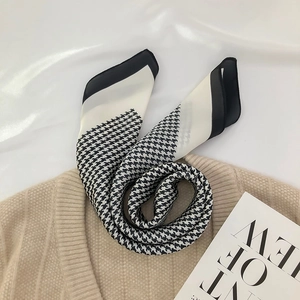 Elegant houndstooth silk scarf with hand-rolled edges on beige knitwear background