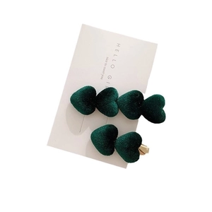 Pair of dark green velvet heart-shaped hair clips on a white card display