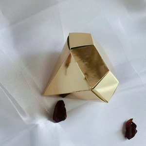 Elegant diamond-shaped golden candy gift box for weddings on a white silk background