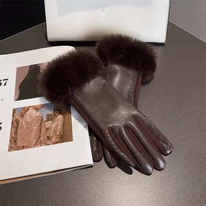 Deep brown PU leather and suede winter gloves with elegant faux fur cuffs on a desk