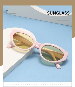 Détail de lunettes de soleil œil de chat roses avec verres jaunes sur support