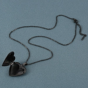 Macro detail of a black heart-shaped locket pendant with an adjustable metal chain