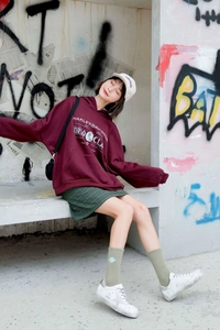Close-up of a burgundy vintage-style hoodie with retro lettering and a large front pocket