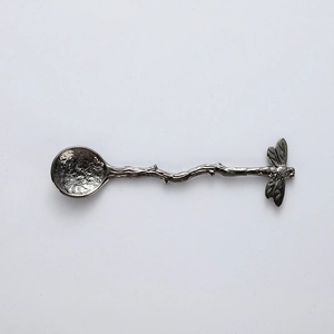 Detailed view of dragonfly handle design and hammered texture on metal dessert spoon