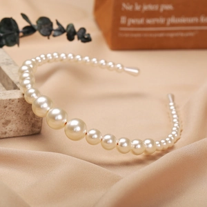 Close-up of elegant gradient imitation pearls on a slim metal headband frame
