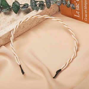 Detailed close-up of a slim gold headband with white pearls on a silk background