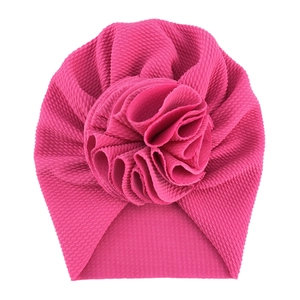Detail of rose pink baby turban hat showing textured waffle fabric and large flower decoration