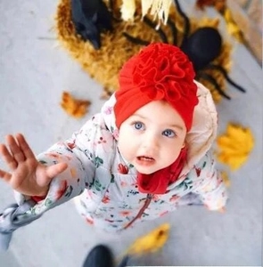 Detail of red baby turban hat with oversized flower, cozy knit cotton fabric for infants