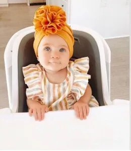 Detailed view of baby mustard yellow turban hat with large 3D flower decoration