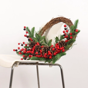 Christmas wreath with red berries and pine cones hanging on a white chair background