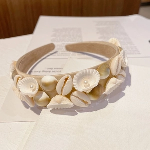 Detail of baroque headband with natural shells and pearls on a beige fabric base