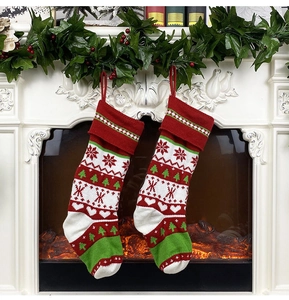 Close-up of knitted red and white Christmas stockings with snowflake patterns on fireplace