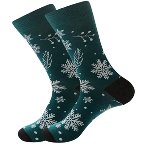 Detail view of dark green knitted Christmas socks with white snowflake and tree patterns