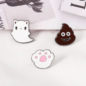 Detailed view of three enamel lapel pins featuring ghost cat, emoji, and cat paw on white texture