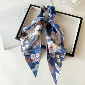 Detail of blue floral satin hair scrunchie with long ribbons in a black display box