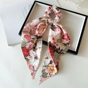 Detailed view of pink floral satin scrunchie with long ribbons on a decorative tray