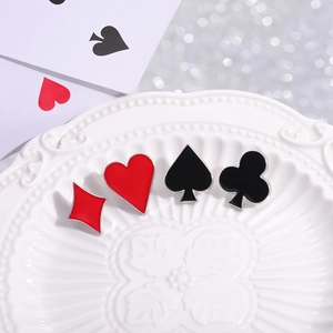 Set of four creative poker suit enamel pins including hearts and spades on a white plate