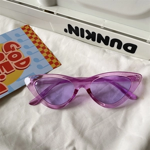Detailed view of purple translucent cat-eye sunglasses on a white textured fabric background