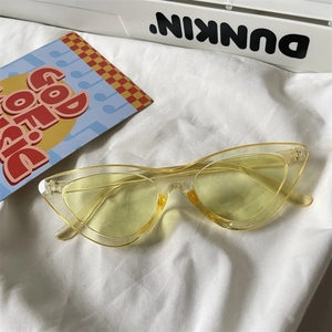 Macro detail of retro yellow cat-eye sunglasses on artistic fabric background