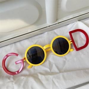 Close-up of yellow children sunglasses with red letter G and D detailing on frames